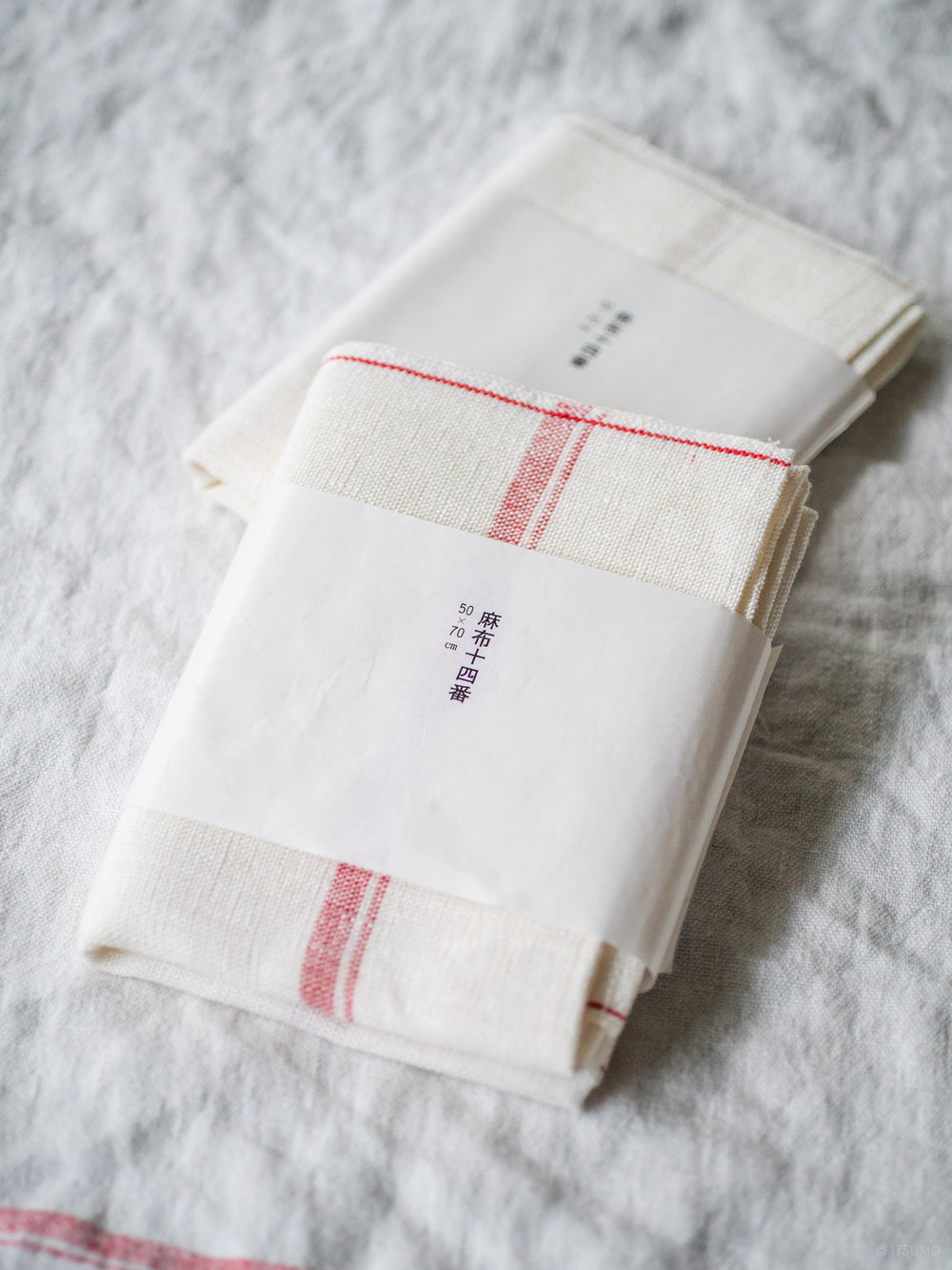 Two Azmaya white azabu linen kitchen cloths, one wth a red stripe, one with a beige stripe