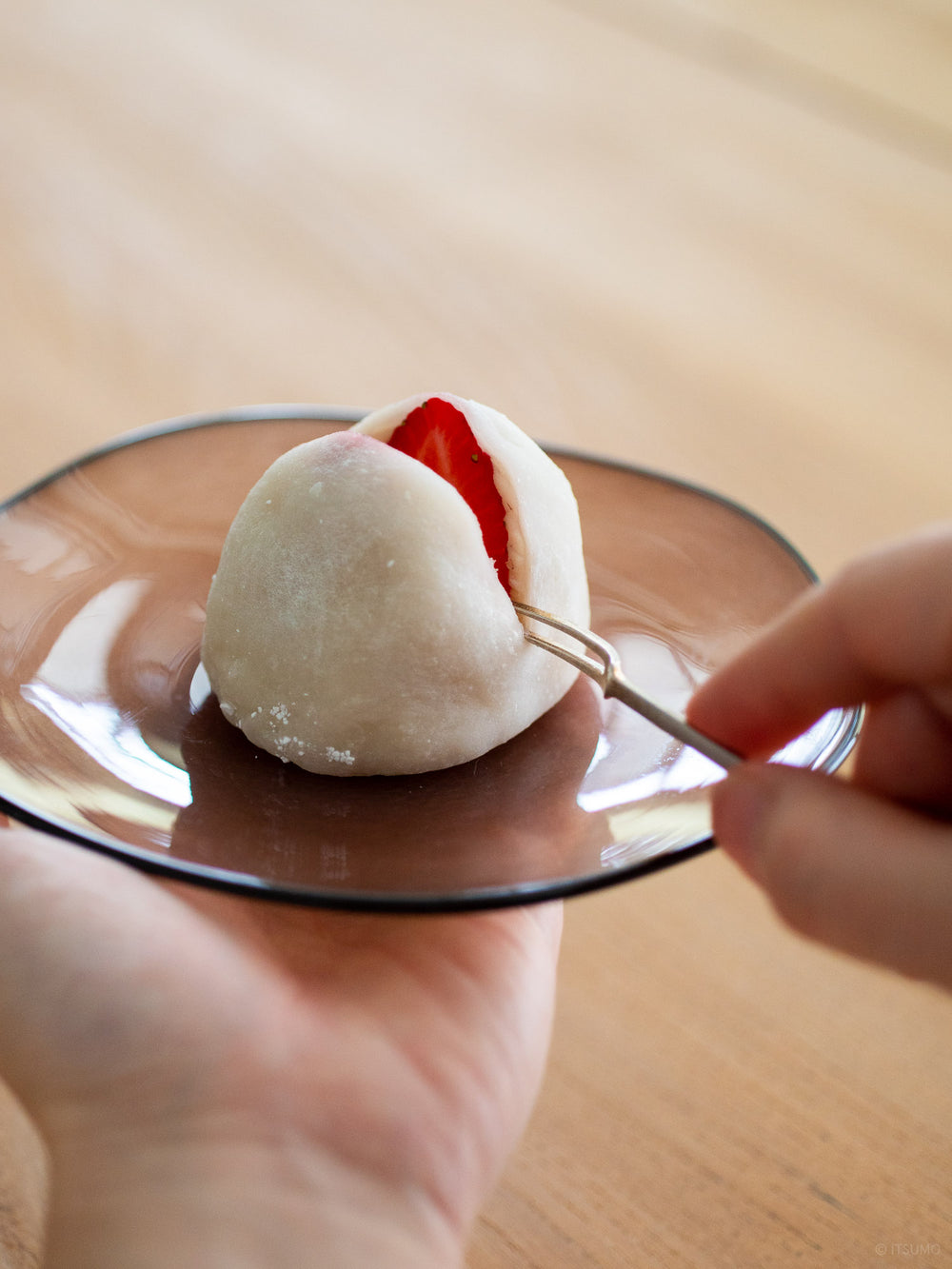 Azmaya brass fork with a strawberry mochi on a glass plate