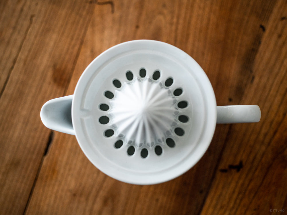 Azmaya's white porcelain citrus juicer top lid with small holes to keep the seeds from falling into the juice