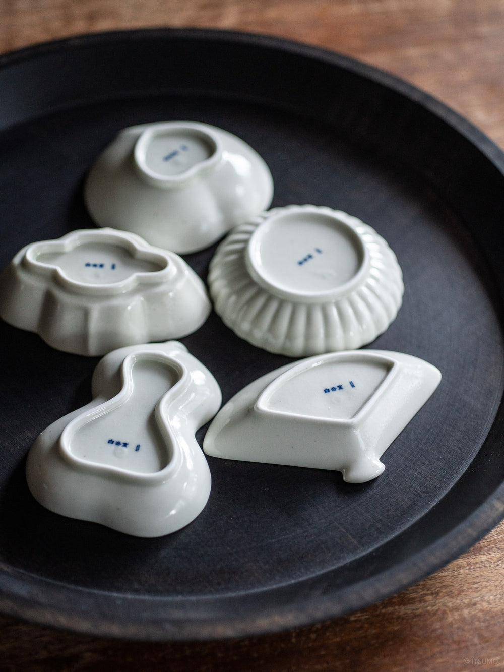 The bottom of five different small Azmaya serving dishes showing a small blue signature