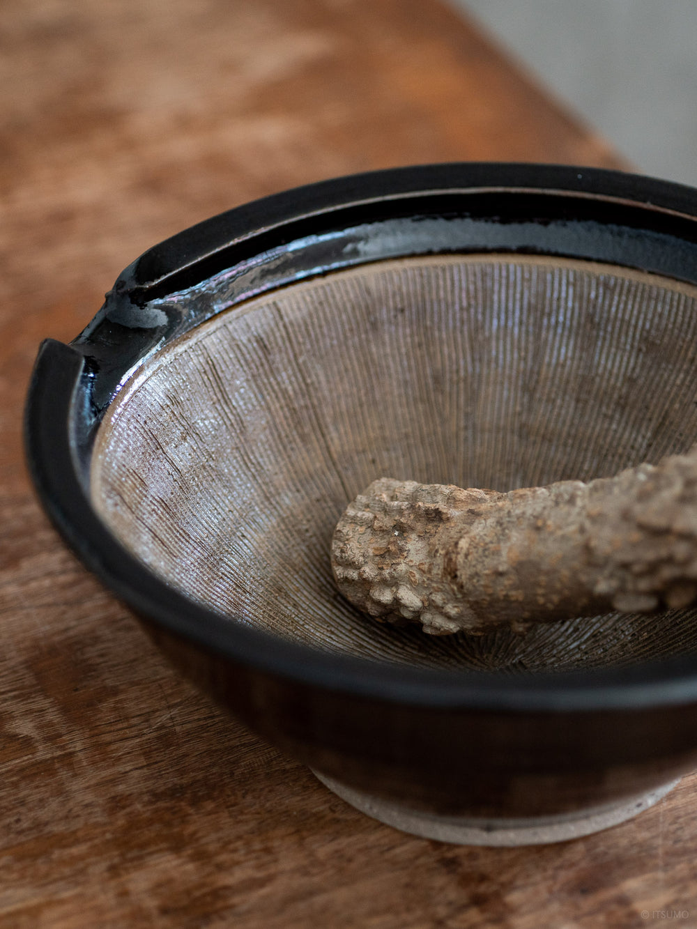 Close up of the inside of the iga suribachi mortar showing textured ceramic lines and a wood pestle