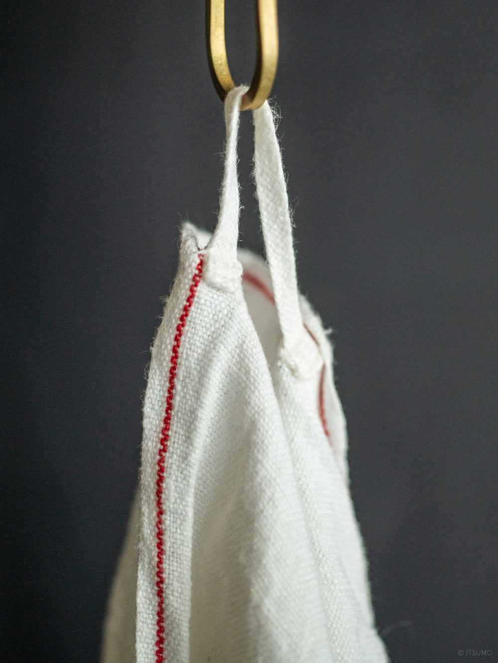 Azmaya white azabu linen hand towel with a red stripe along the edge, hanging from a hook