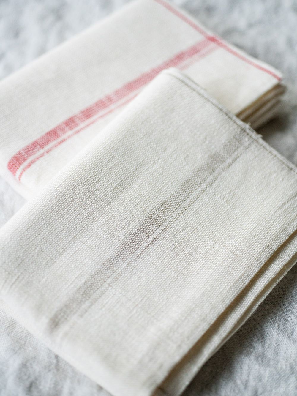 Two azabu linen kitchen towels, one with a red stripe and one with a beige stripe