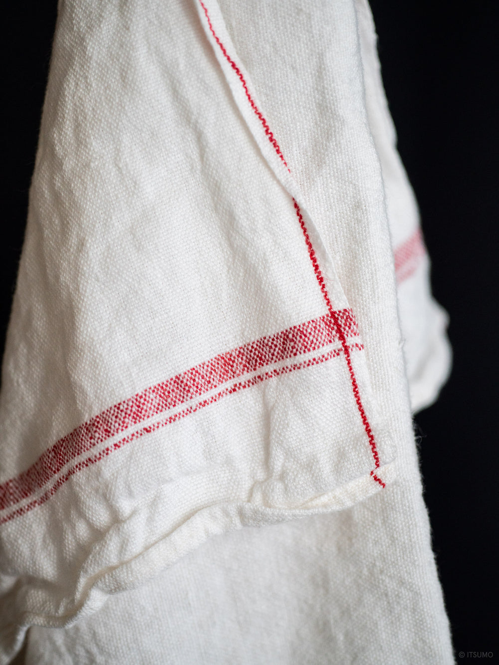 Close up texture of white azabu linen kitchen cloth with a red stripe along the edge