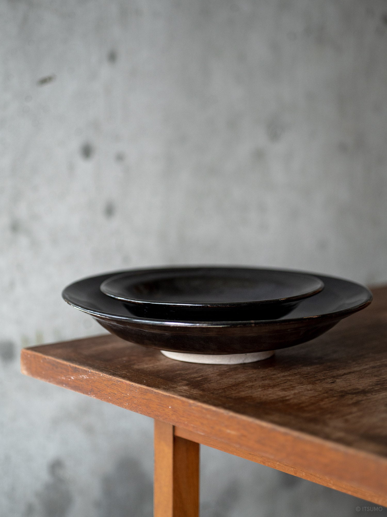 Two Azmaya Iga ware black ceramic plates in Kuroame glaze