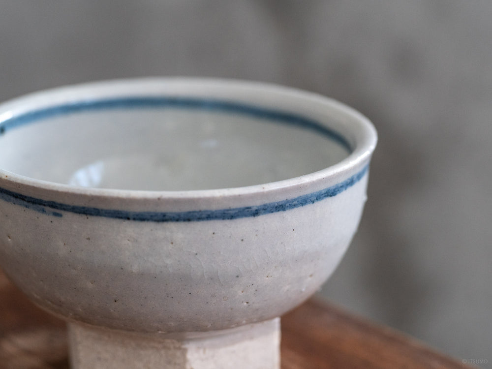Small iga ware ceramic bowl with hexagon base in white glaze with a blue stripe