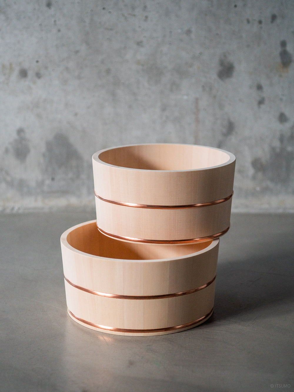 Two Azmaya hinoki wood bath bowls with copper trim around the middle and bottom
