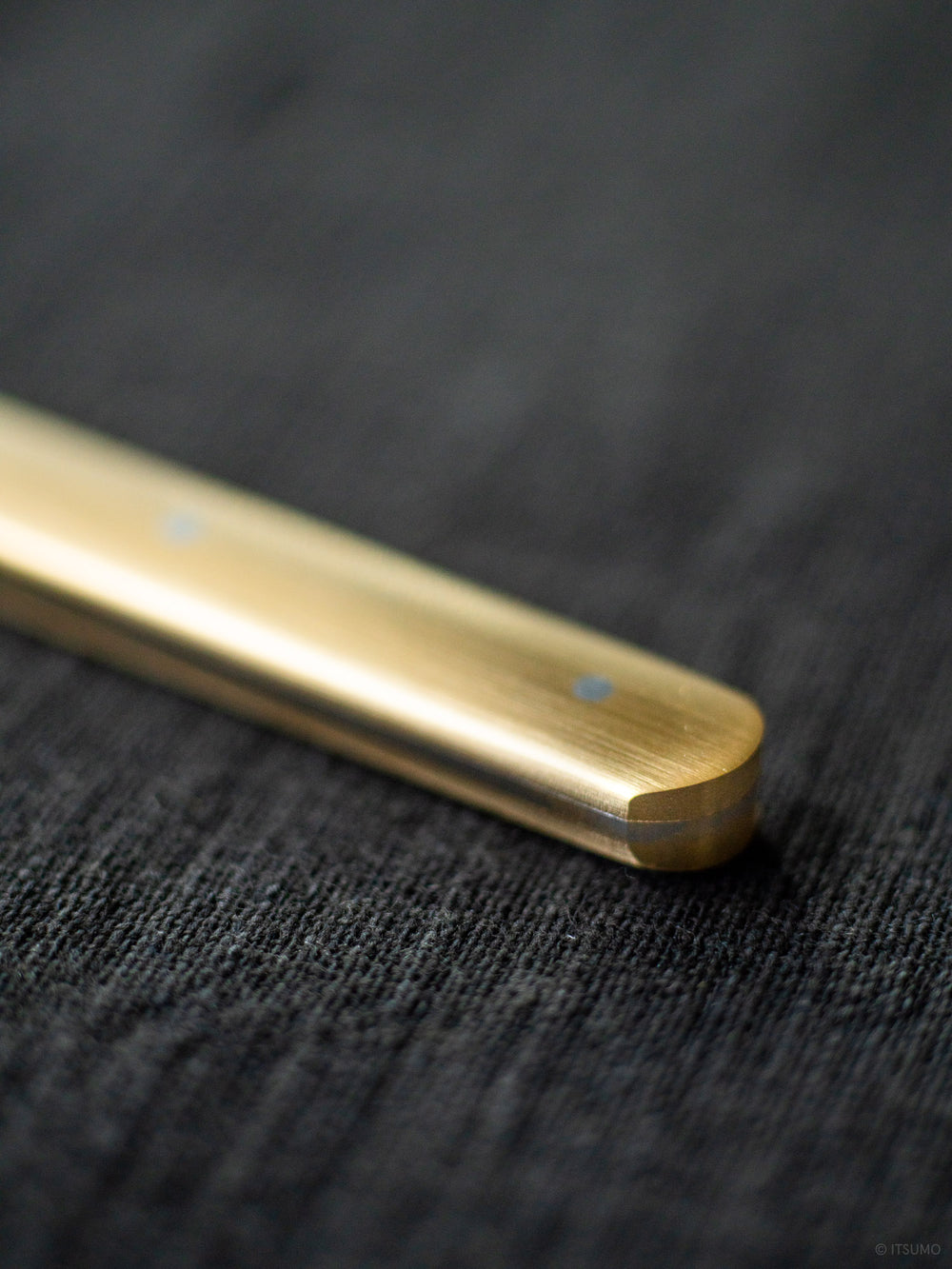 Brass handle close up details showing a slightly round edge, on a stainless steel cheese knife made in Japan