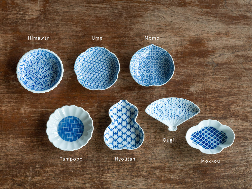 Six small Azmaya white porcelain dishes with a blue pattern inside, shaped in various traditional Japanese motifs like peaches and sunflowers