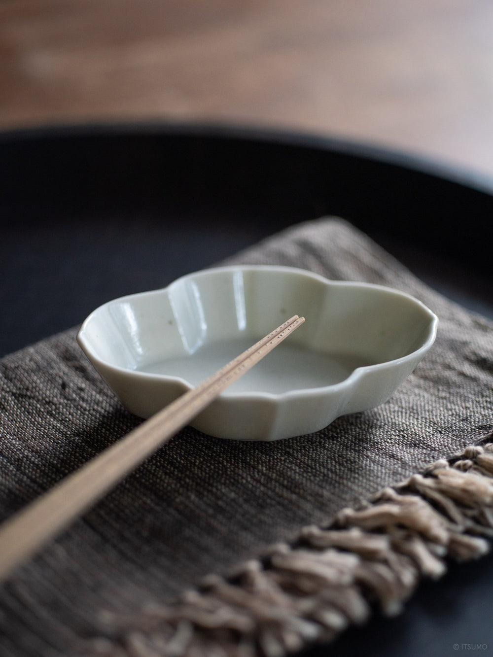 Close up of a small Azmaya serving dish for soy sauce or garnishes, with some chopsticks