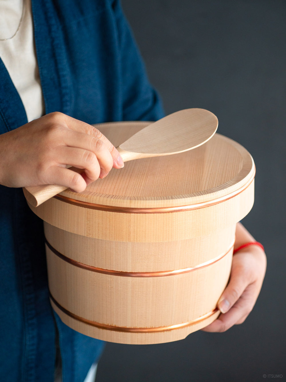 Hands holding a kiso sawara ohitsu rice chest with serving spoon