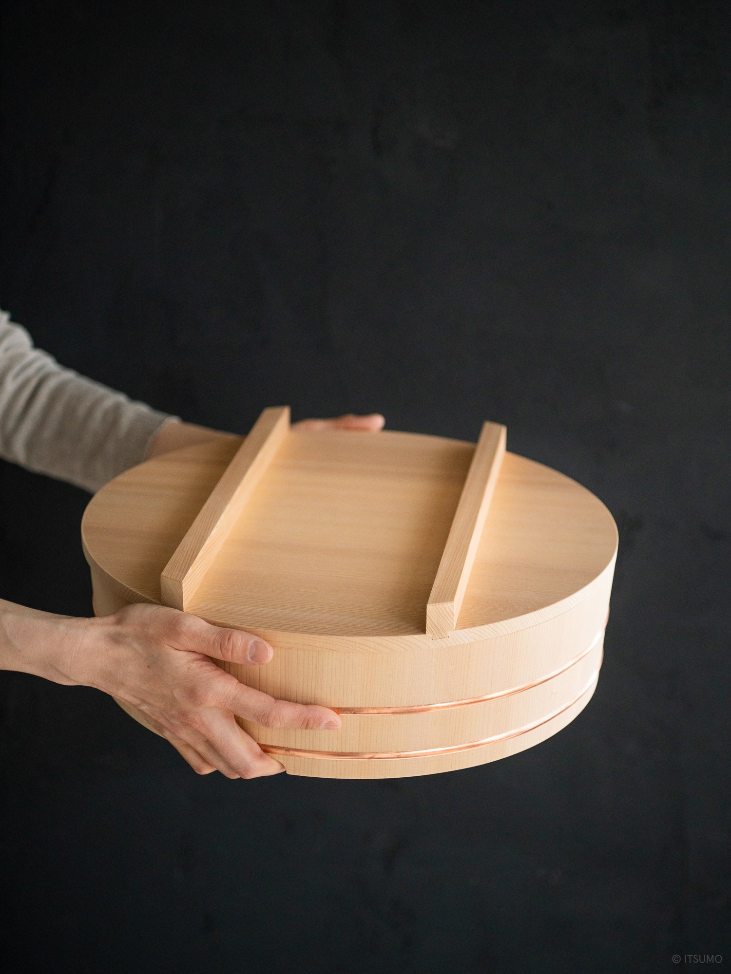 Hands holding a large Azmaya kiso sawara sushi rice mixing bowl