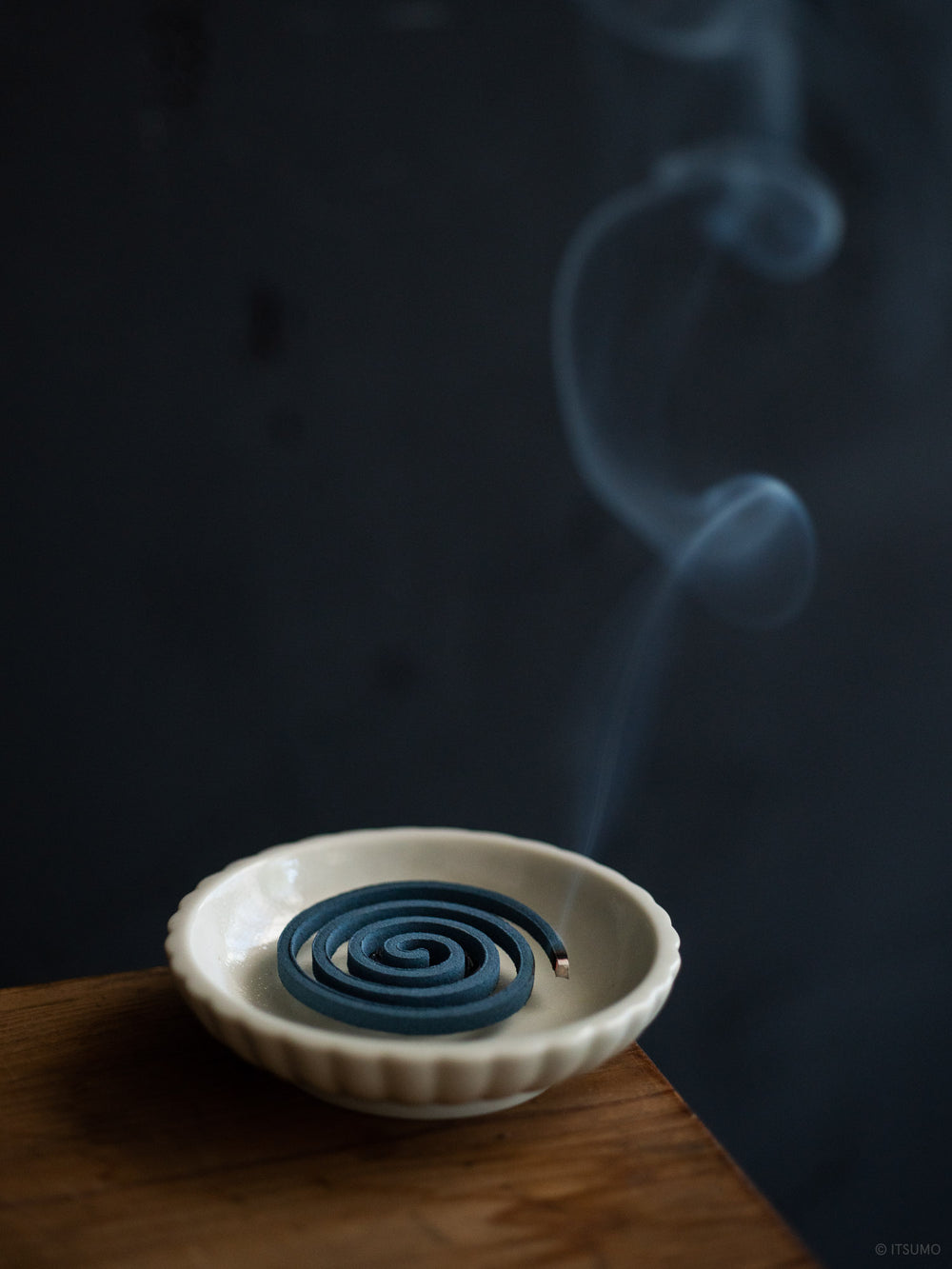Small Azmaya porcelain dish holding a burning incense coil